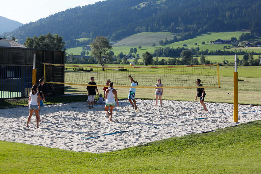 Al campo estivo Austria alcuni ragazzi giocano nel campo di beach volley in mezzo alle montagne