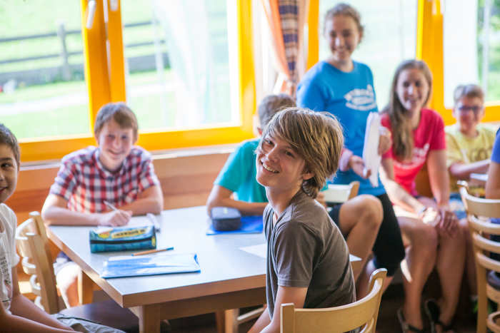 Al campo estivo in inglese un bambino ascolta interessato con gli amici
