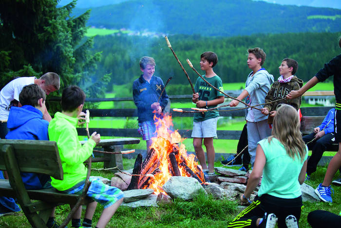 Durante la vacanza estiva per ragazzi un gruppo è radunato attorno al falò per arrostire i marshmallows