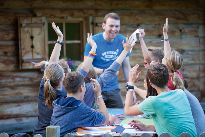 I ragazzi del campo estivo in inglese alzano la mano insieme per rispondere all'insegnante