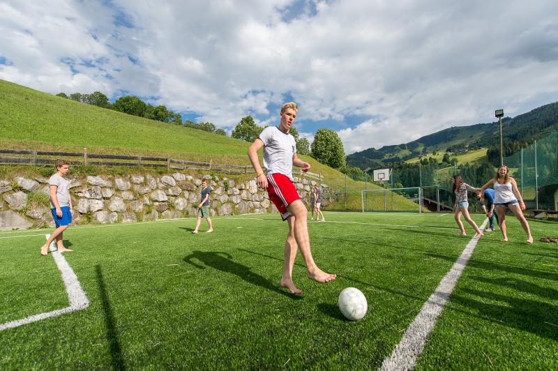Un ragazzo del campo estivo Austria gioca a calcio nel prato circondato da altri ragazzi e ragazze del gruppo