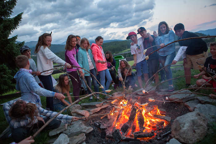 Al campo avventura in Austria, i ragazzi stanno accendendo un falò all'aperto e mangiando dei marshmallow 
