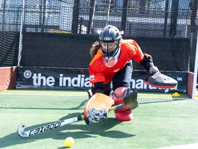Al campo estivo hockey ad Amsterdam c'è una ragazza che sta giocando ai hockey parando una palla