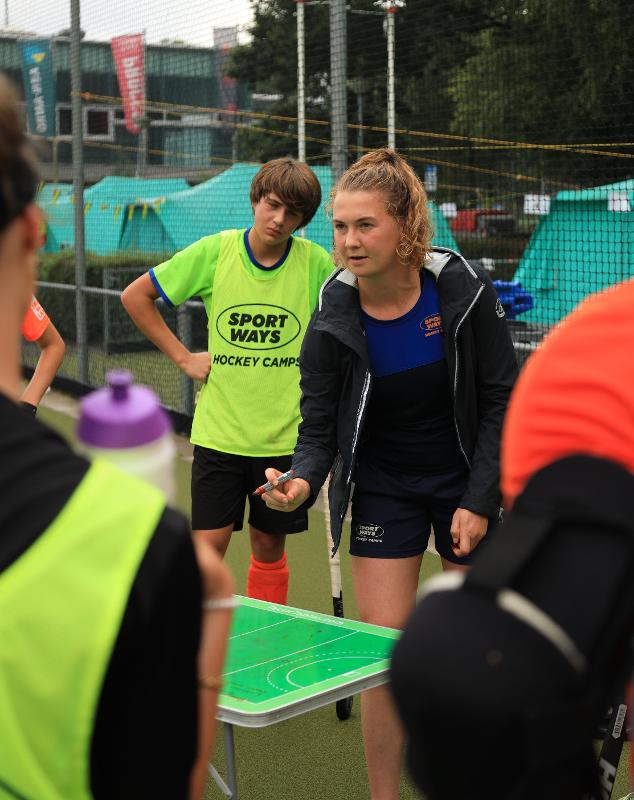Al campo estivo hockey ad Amsterdam l'allenatrice sta spiegando le tecniche di gioco agli allievi 
