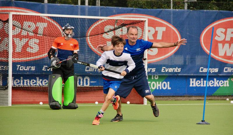 Al campo estivo hockey ad Amsterdam ci sono due ragazzi che si stanno allenando insieme al coach