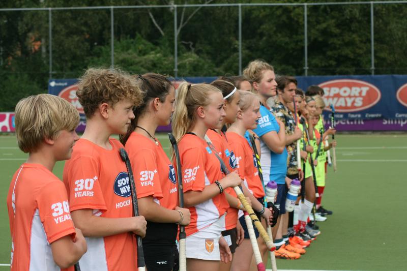 Al campo estivo hockey Anversa ci sono ragazzi e ragazze che sono posizionati in fila pronti per giocare