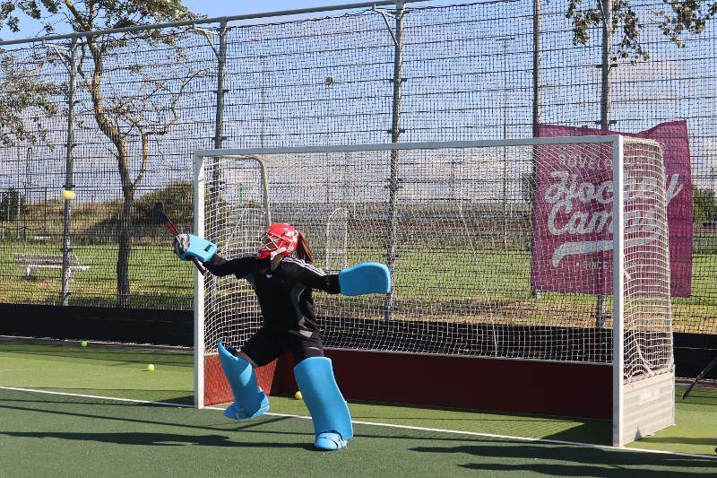 Una ragazza si tuffa per parare una palla al campo estivo hockey