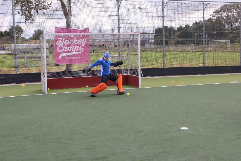 Un portiere del campo estivo hockey para un tiro con il piede sinistro