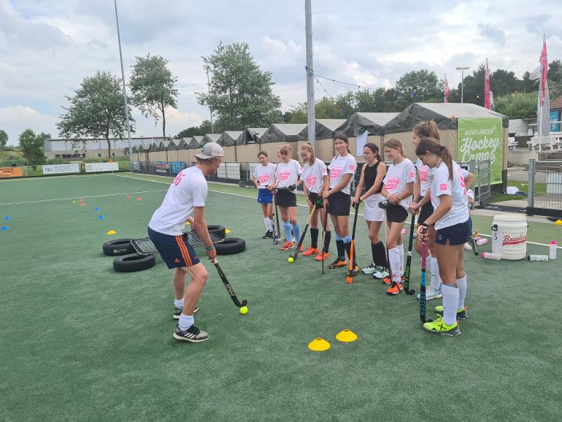 Le ragazze del campo estivo hockey ascoltano attentamente l'allenatore
