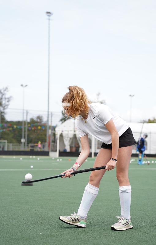 Una ragazza controlla la palla sulla mazza al campo estivo hockey