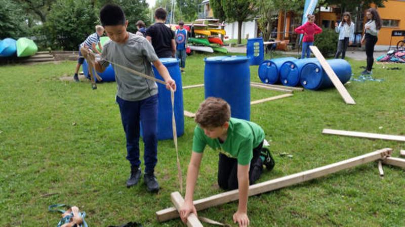 Al campo internazionale sul Lago Costanza ci sono due bambini che stanno imparando a costruire una zattera