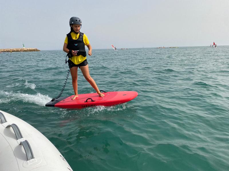 Una bambina del campo estivo Calabria indossa le protezioni e prova a cavalcare la tavola in mare