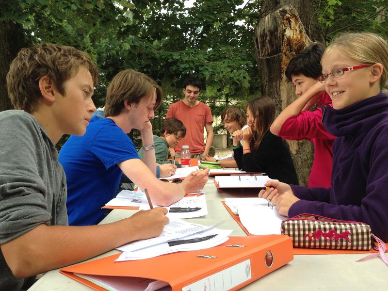 Un gruppo di ragazzi del soggiorno linguistico francese sono seduti ad un tavolo a studiare e conversare