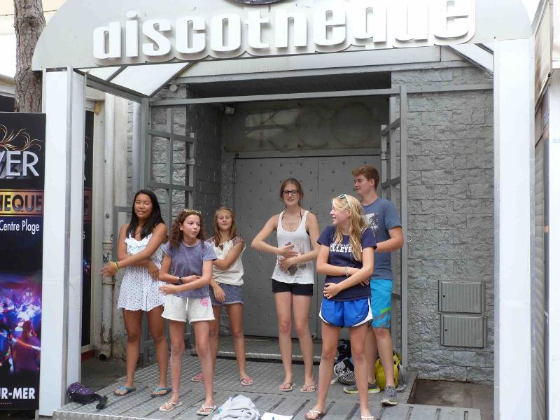 Alcuni ragazzi del soggiorno linguistico in francese fanno un balletto fuori da una discoteca di giorno