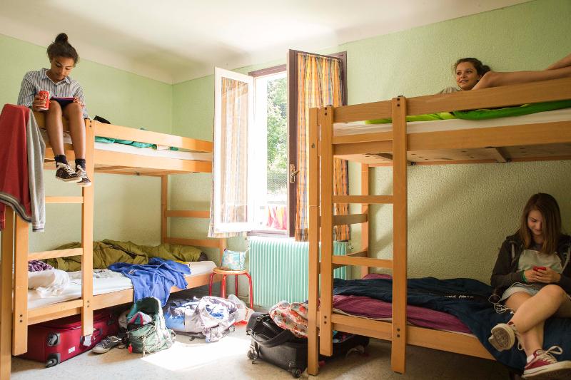 Si vede una stanza da tre letti a castello del soggiorno linguistico francese in cui tre ragazze si stanno rilassando sui loro rispettivi letti