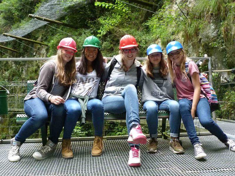 Ai campi estivi per ragazzi in Italia alcune ragazze con i caschetti colorati siedono su una panchina
