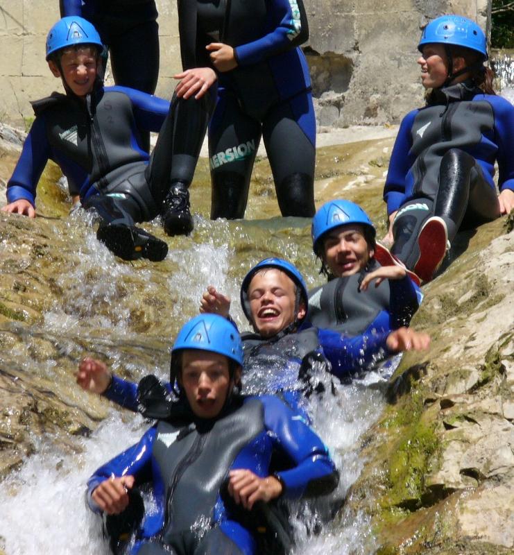 I partecipanti del soggiorno linguistico francese scivolano giù per le cascate e i torrenti del fiume