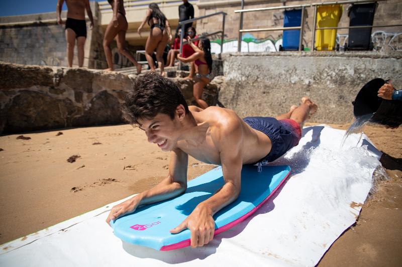 Al campo estivo mare un ragazzo si sdraia su una tavola e scivola giù in uno scivolo d'acqua sulla spiaggia