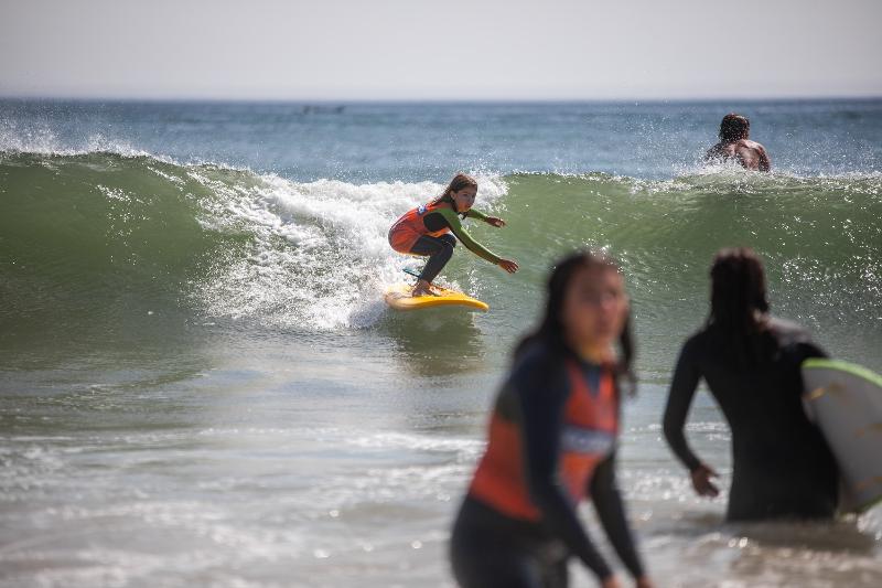 Una bambina surfa prendendo le onde ai surf camps Spagna