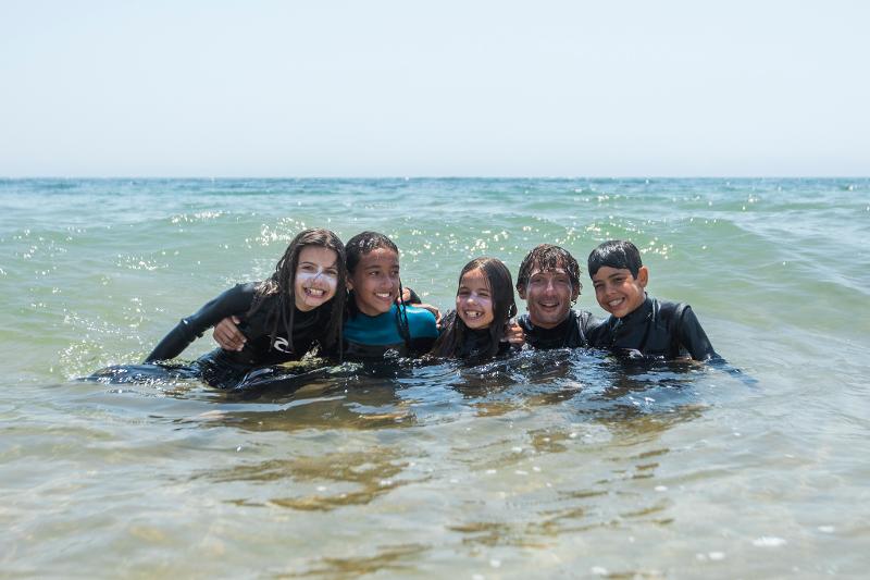 Tre bambini e l'istruttore sono immersi in mare con le mute al campo estivo mare