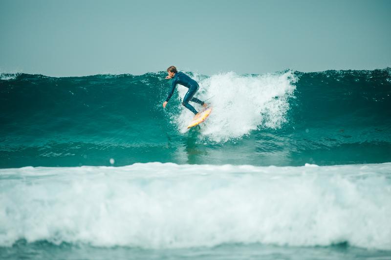 Un ragazzo cavalca un onda al surf camp estivo Lisbona