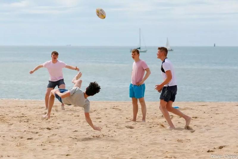 Ai corsi francese Francia un gruppo di ragazzi gioca a pallone in spiaggia