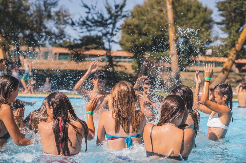 Al campo estivo nuoto, i ragazzi sono in piscina all'aperto e giocano schizzandosi con l'acqua