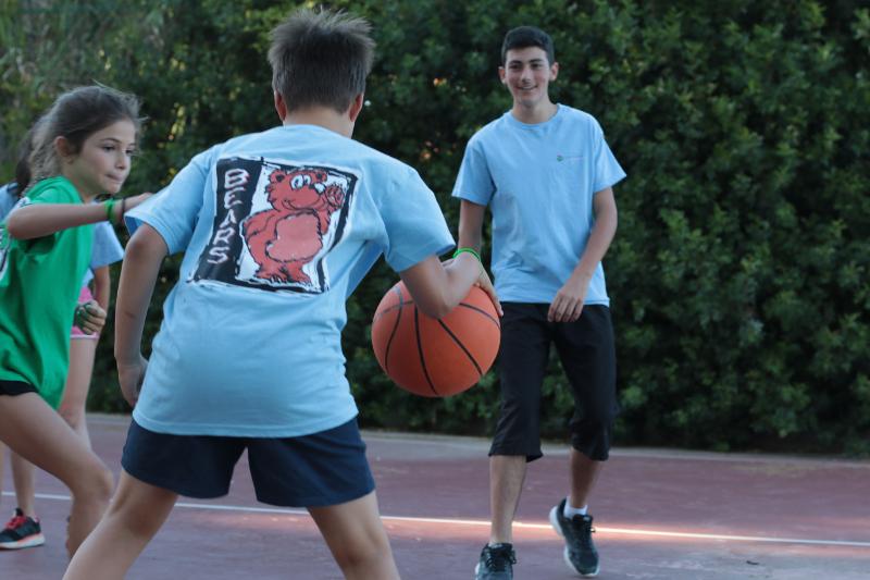 Due ragazzi e una bambina giocano a basket al campo estivo attività in Spagna