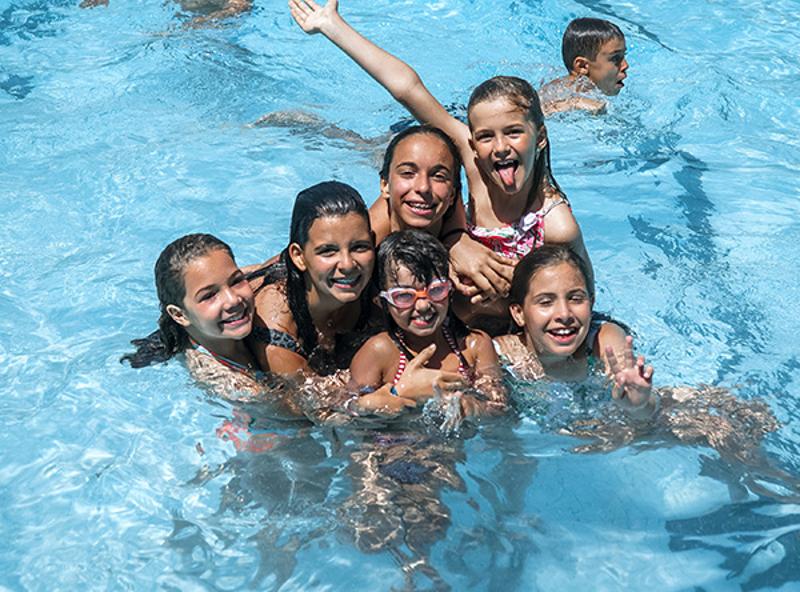 Bambine che posano e giocano in piscina al campo estivo