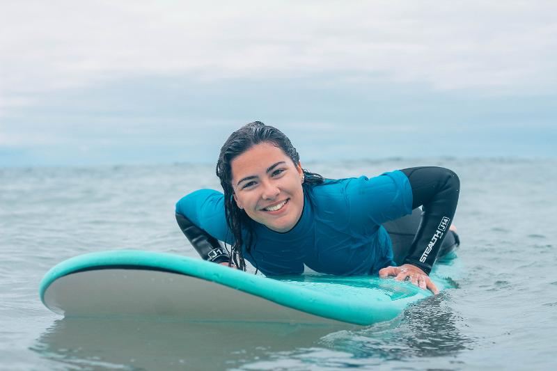 Una ragazza del campo estivo Campania è sdraiata su una tavola da surf azzurra in mare