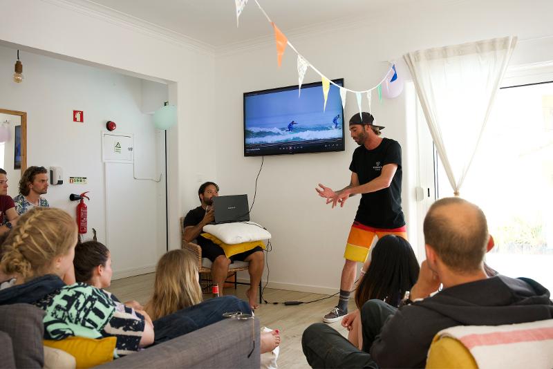 L'istruttore del campo estivo surf presenta una lezione ai ragazzi mostrando delle riprese sul televisore