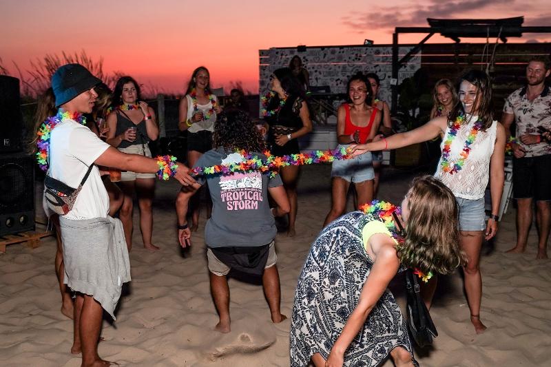 I partecipanti del campo estivo surf giocano al limbo sulla spiaggia durante una serata organizzata