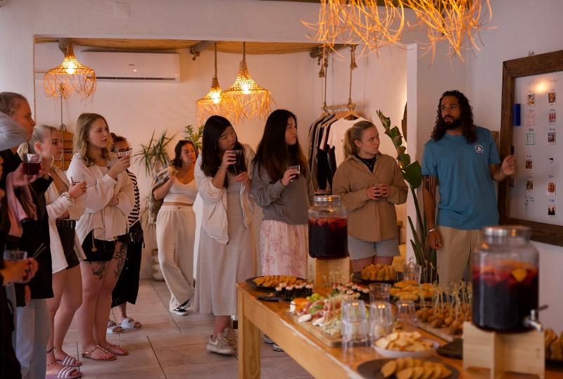 I partecipanti del campo estivo surf mangiano dal buffet e ascolano attentamente un istruttore