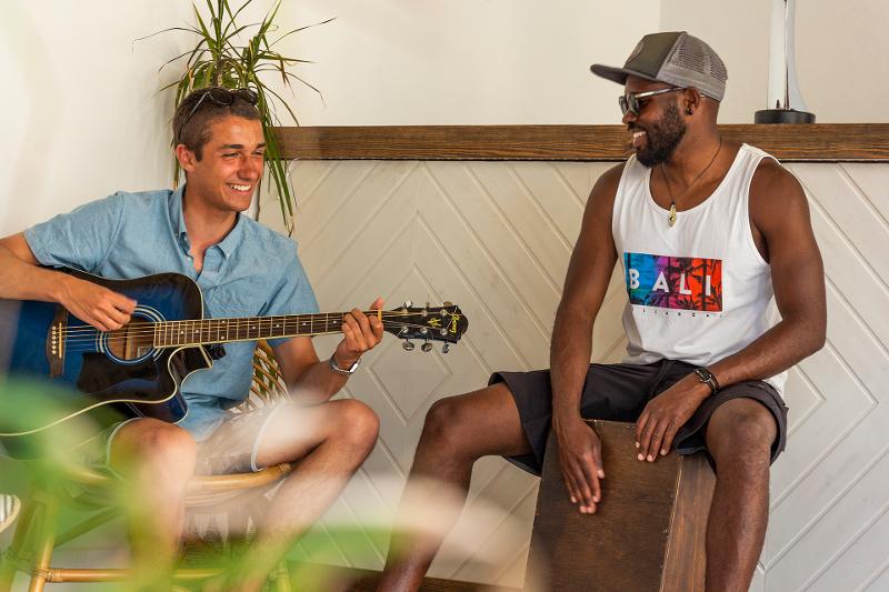 Due ragazzi suonano la chitarra e sono felici al campo estivo surf
