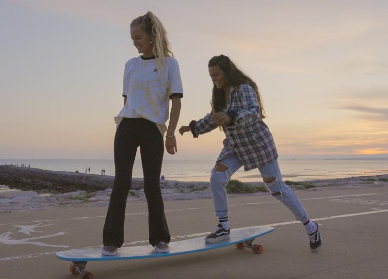 Due ragazze si spingono su una tavola da surf con le ruote al surf camp Sardegna