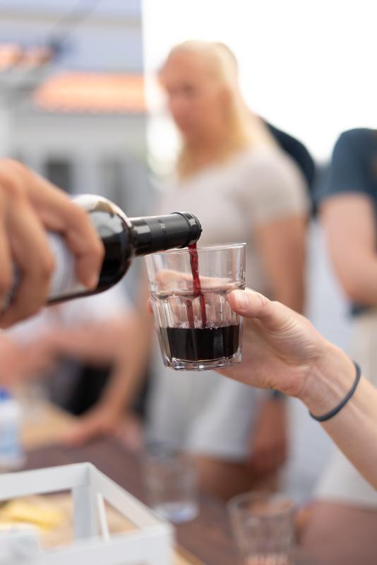 Un ragazzo del camp estivo surf versa un bicchiere di vino rosso