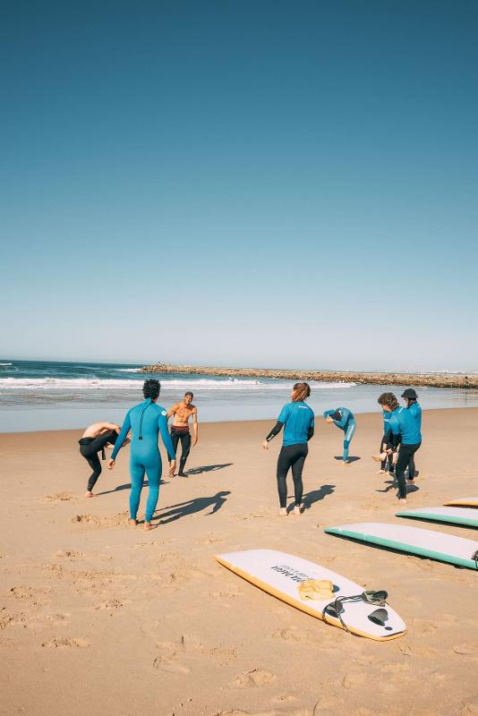 I partecipanti del campo estivo surf si riscaldano sulla spiaggia prima di entrare io acqua