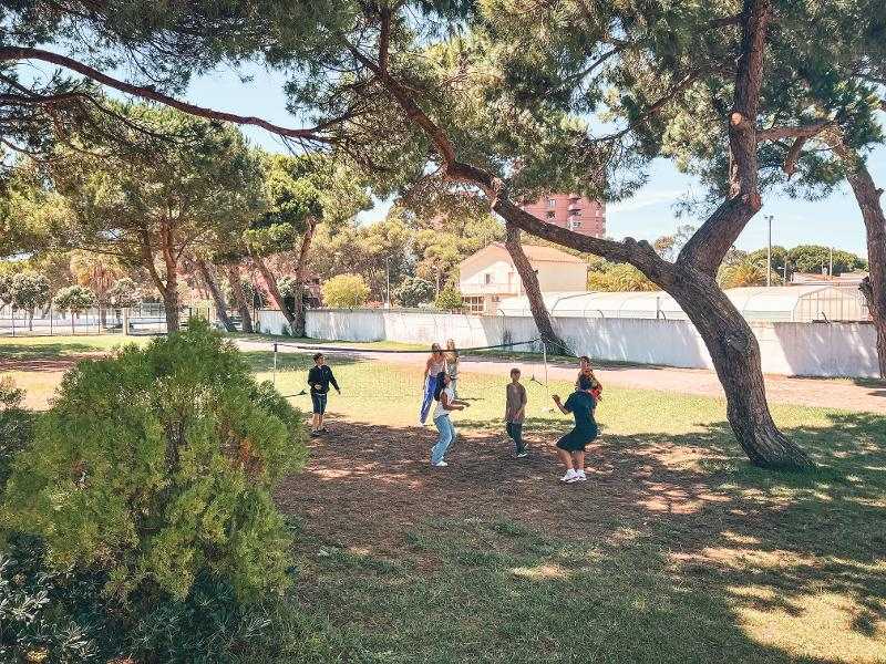 Alcuni partecipanti del campo estivo surf giocano a pallavolo in un parco