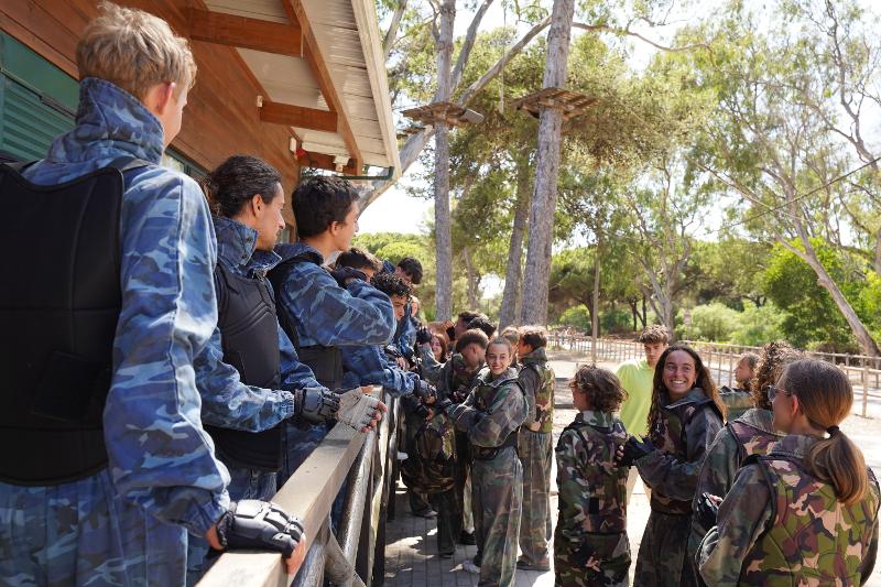 I partecipanti sono vestiti con tute militari e stanno per scontrarsi in una sessione di paintball