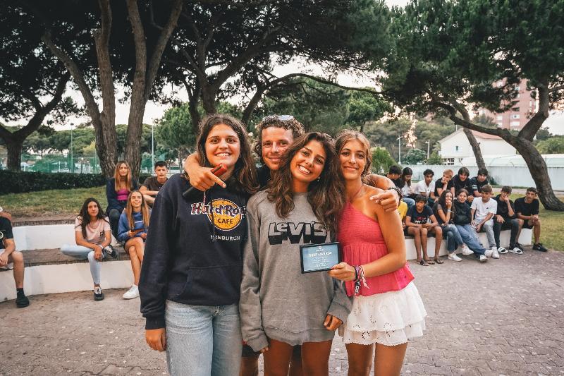 Quattro amici del campo estivo surf si abbracciano per la fotografia