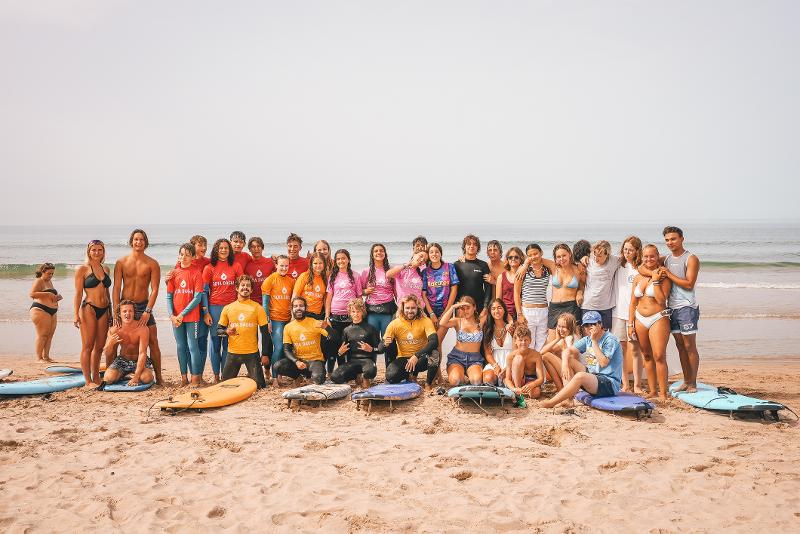 Tutto il gruppo del campo estivo surf è riunito in riva al mare per scattare una fantastica foto di gruppo