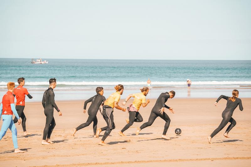 I ragazzi del campo estivo surf giocano a calcio in spiaggia