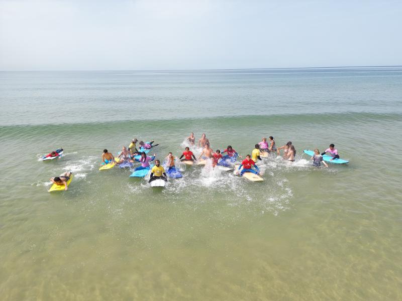 Il gruppo del campo estivo surf è riunito in acqua e aspewtta le onde perfette