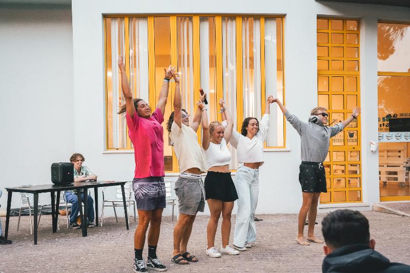 Cinque partecipanti del campo estivo surf si esibiscono davanti al resto del gruppo