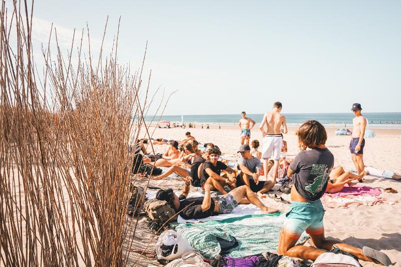 Un gruppo di partecipanti del campo estivo surf prende il sole in spiaggia