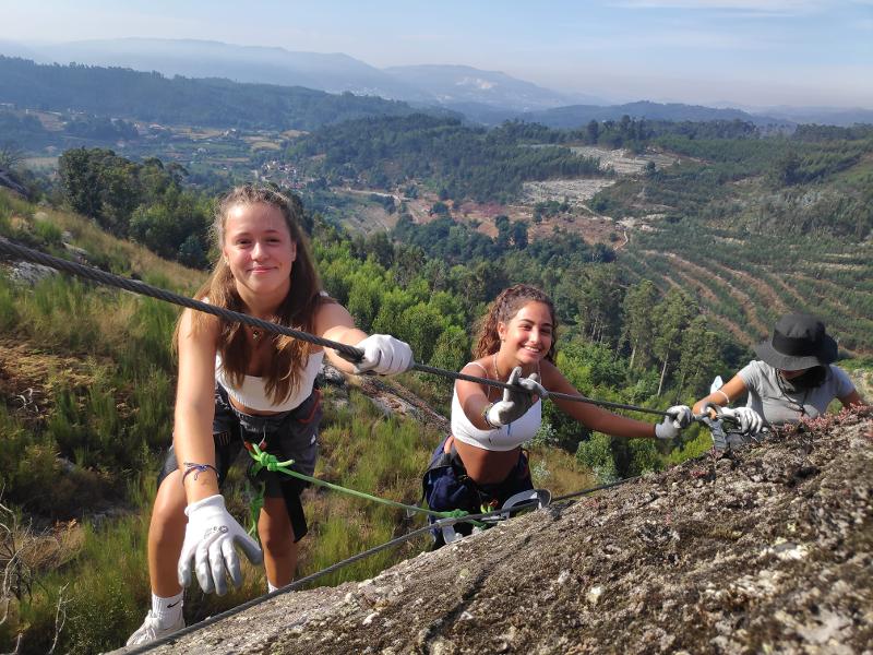 Alcune ragazze provano a scalare un'altura con le protezioni e le corde al campo estivo Portogallo