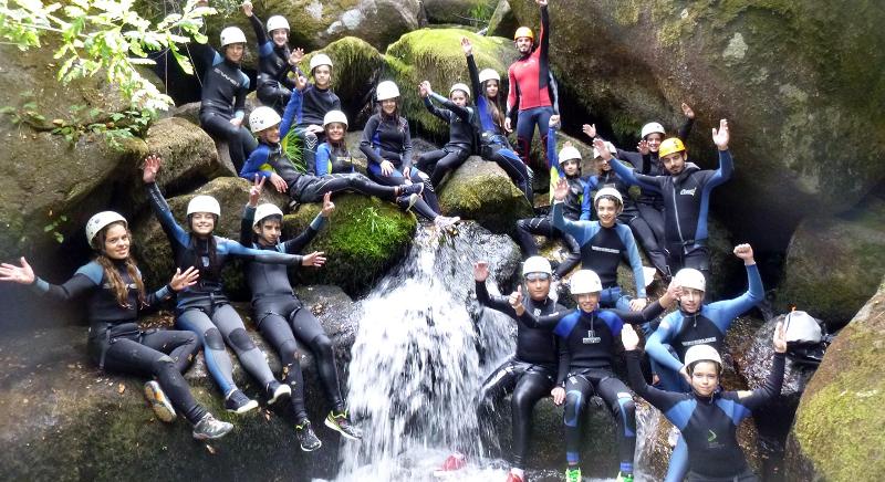 Al campo avventura in Portogallo i ragazzi siedono su alcune rocce vicino a una piccola cascata nel verde
