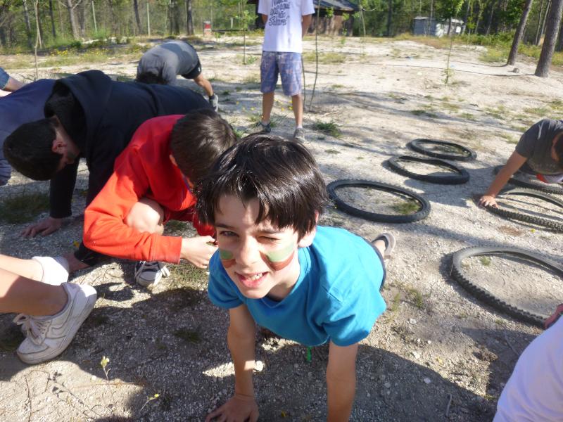 Un bambino del campo estivo Portogallo ha il viso pitturato di verde e marrone e esegue un percorso
