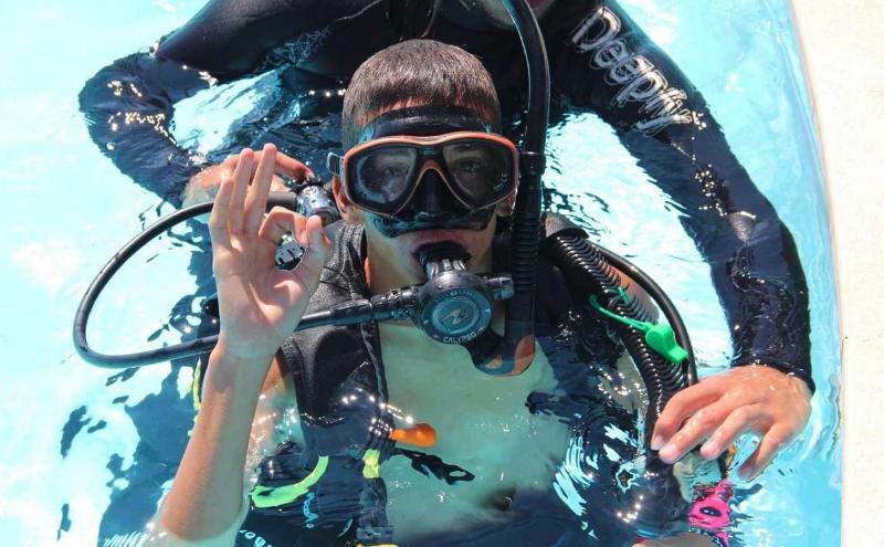 Un ragazzo al soggiorno linguistico Inghilterra è in acqua e indossa l'attrezzatura da sub