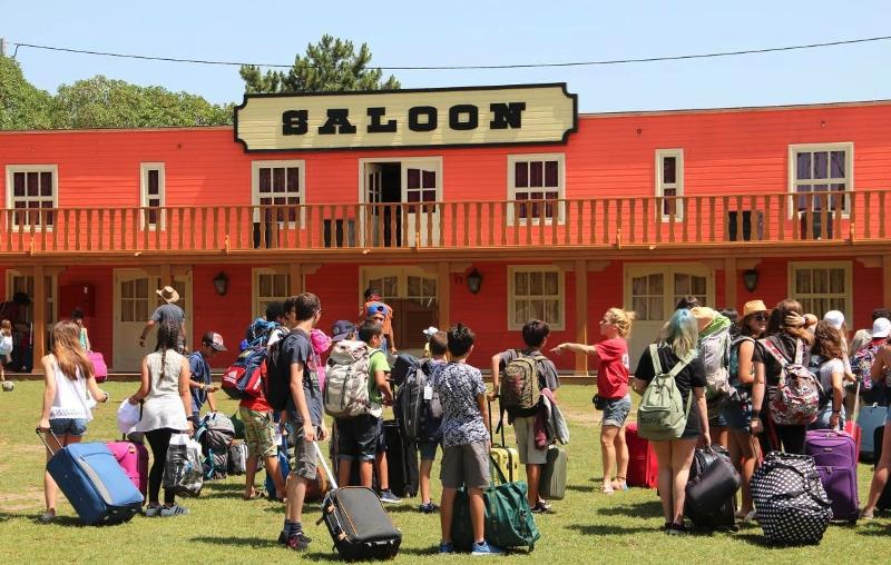 Nel viaggio per ragazzi all'estero tanti ragazzi si trovano con le loro valigie davanti a un edificio che ricorda un vecchio saloon americano